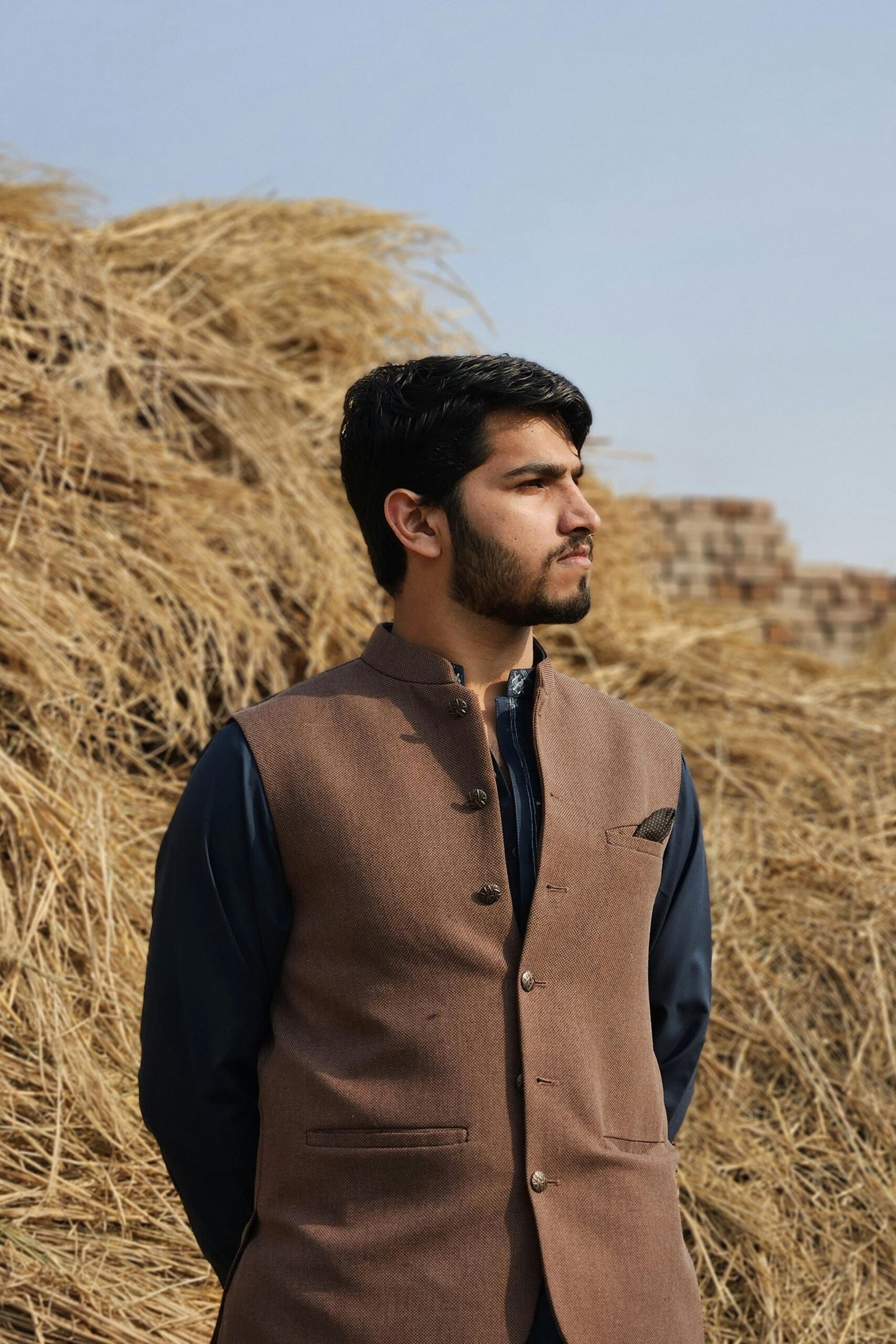 A fashionable man in traditional shalwar kameez stands confidently outdoors.